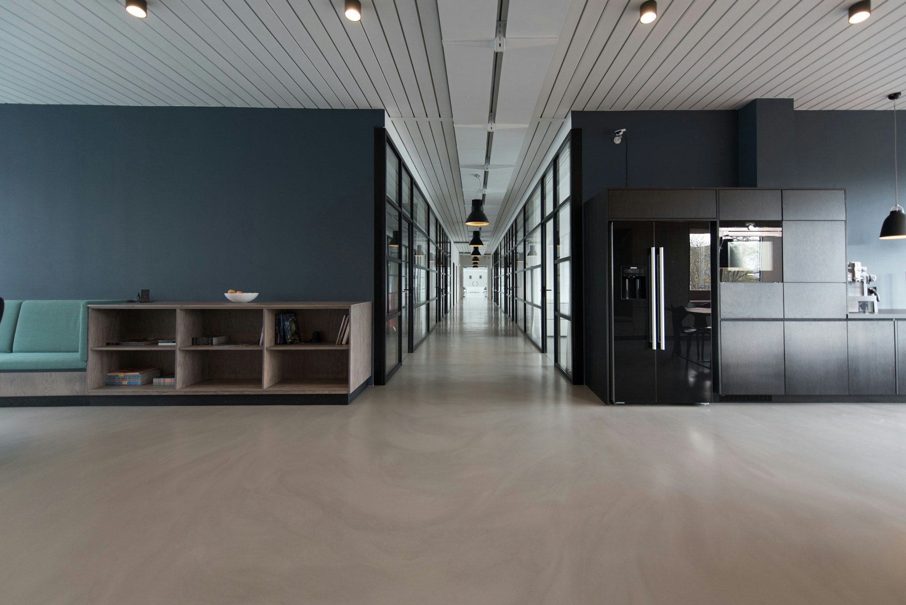 Interior of a long bright architecture studio with drafting tables, scale models, and a central courtyard view