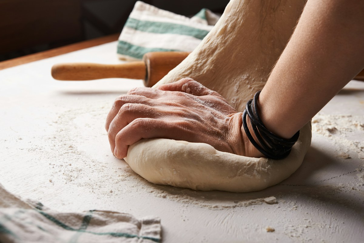 A cardamom bun on a ceramic plate, mid-process